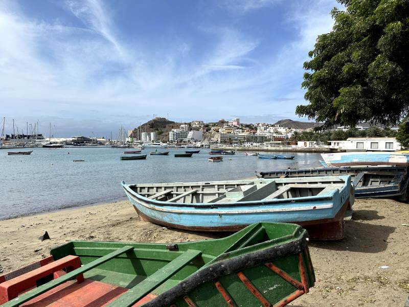 Puerto de Mindelo Varias barcas tradicionales de colores estacionadas en la arena junto al puerto de Mindelo