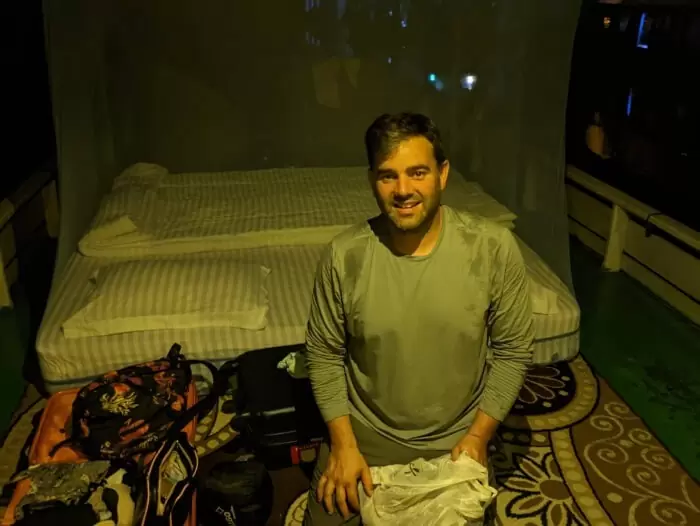 Jordi en nuestro klotok y detrás nuestra cama con la mosquitera ya preparada porque ha anochecido