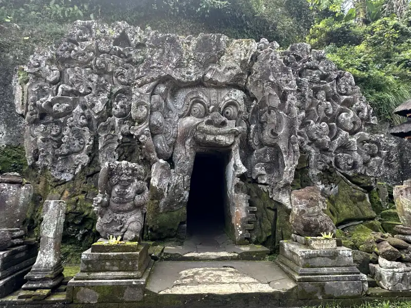 Cueva Goa Gajah tallada con formas demoníacas, donde la boca abierta de un gran rostro forma la entrada a la cueva