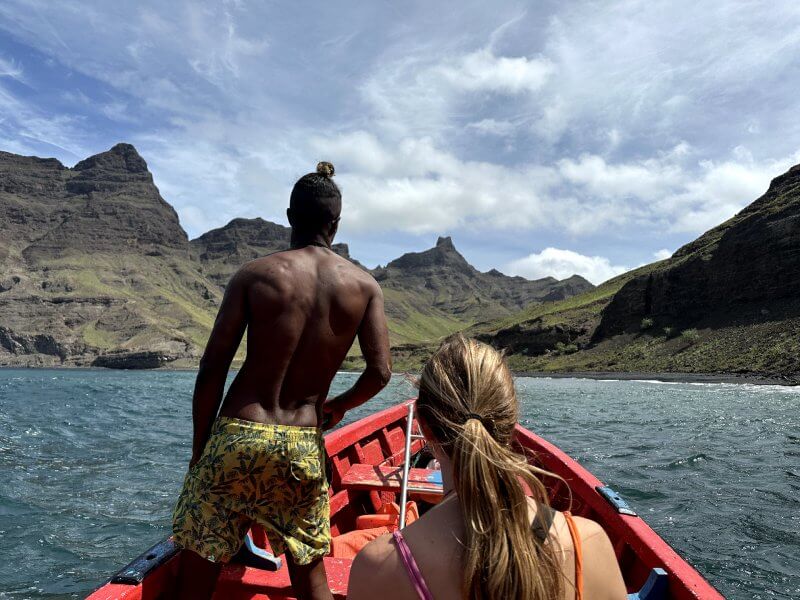 Mi amiga Eli y uno de nuestros guías de espalda, a bordo de una barca de pescadores con las vistas de las montañas y del mar de fondo