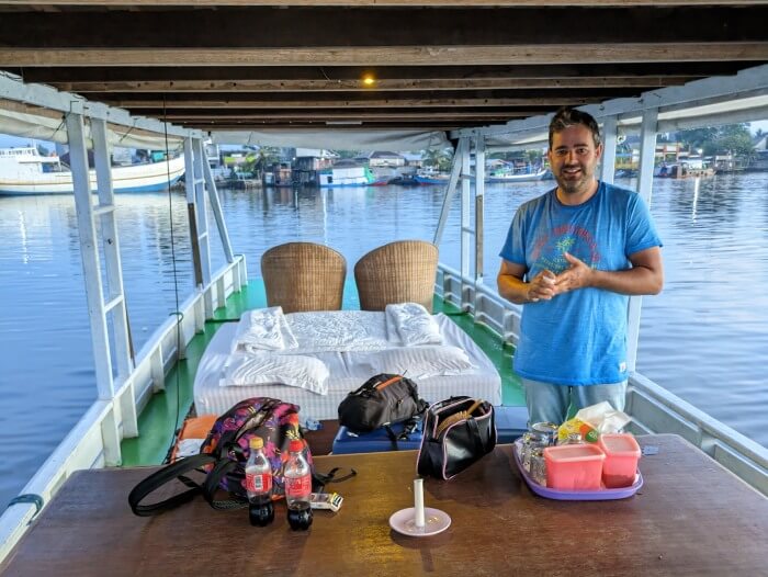 Jordi en nuestro klotok de la excursion para ver orangutanes en Borneo y el puerto de Kumai al fondo