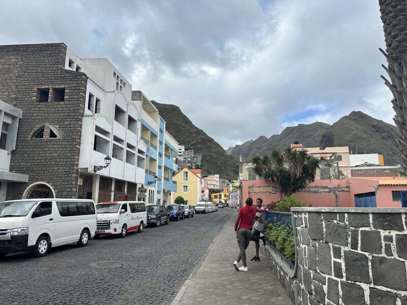 Una de las calles comerciales de Ribeira Grande donde compramos nuestra sim para viajar a cabo verde por libre y las montañas de Santo Antao al fondo