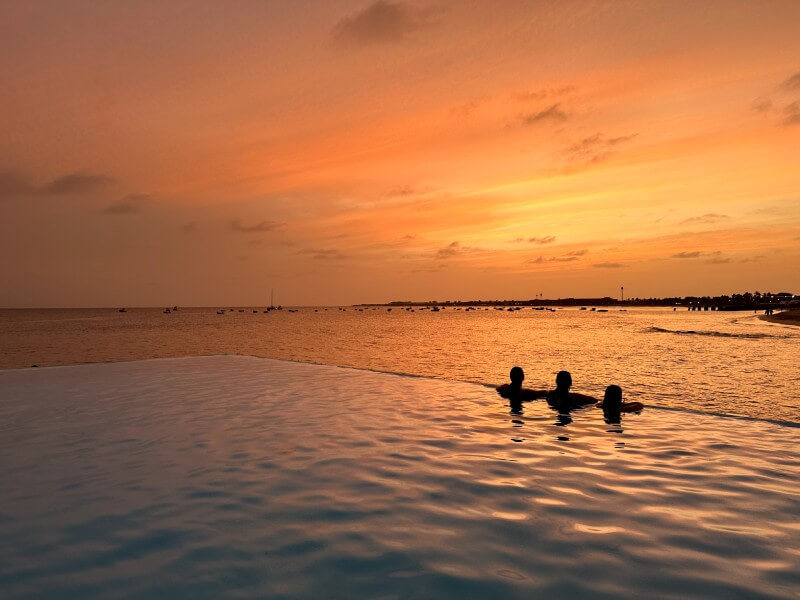 Nosotras de espalda en la piscina infinita de nuestro hotel con el mar enfrente, contemplando el atardecer en Santa Maria. El mejor final para nuestra ruta de 7 dias por Cabo Verde