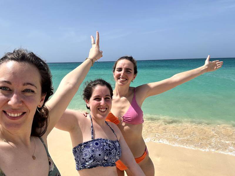 Mis amigas y yo sonriendo delante de las aguas turquesa de la playa Ponta Preta