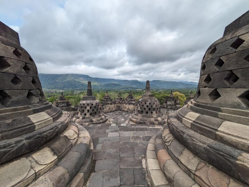 Vista panoramica desde lo alto del templo Borobudur dpnnde pueden observarse las pagodas en primer plano y el paisaje verde y lleno de niebla al fondo