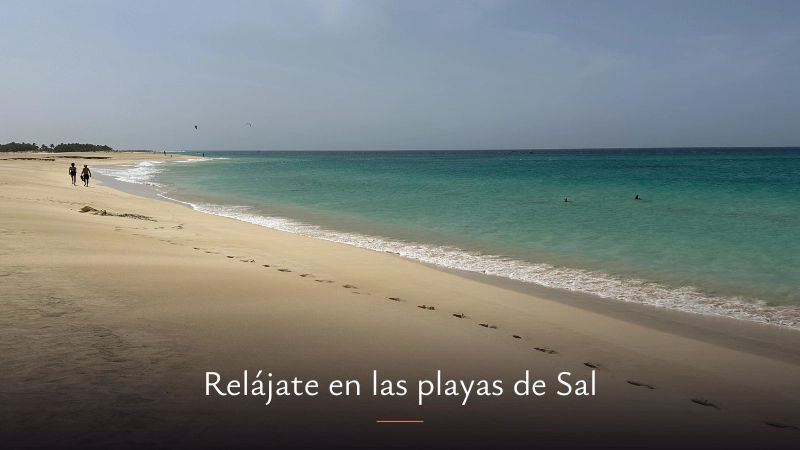 Vistas de la playa Ponta Preta donde pueden verse las aguas azul turquesa, la arena ligeramente dorada y dos personas andando hacia el horizonte